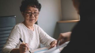 senior woman having discussion with her agent about her retirement investment plan signing legal document
